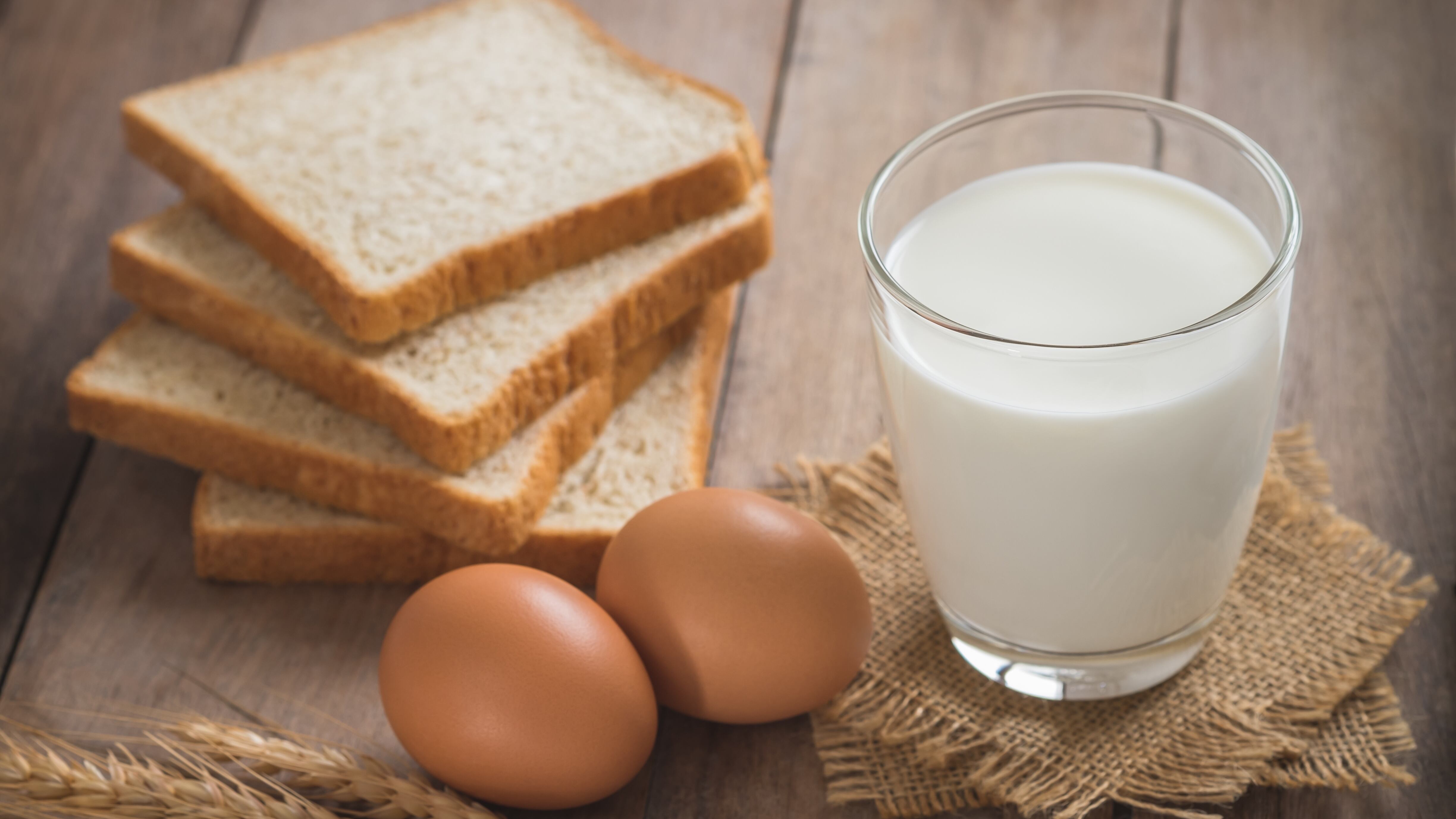 Milk glass with egg and bread on wooden table