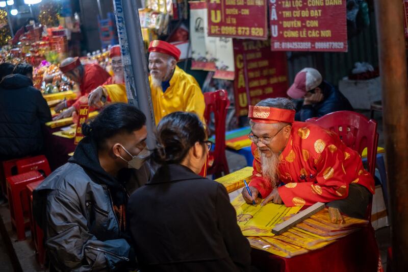 HANOI, VIETNAM - FEBRUARY 10: A calligrapher writes down wishes to visitors to mark the start of the Lunar New Year on February 10, 2024 in Hanoi, Vietnam. Lunar New Year, also known as Chinese New Year. The day is celebrated around the world, and The Year of the Wood Dragon in 2024 is associated with growth, progress, and abundance, as wood represents vitality and creativity, while the dragon symbolizes success, intelligence, and honor. (Photo by Linh Pham/Getty Images)